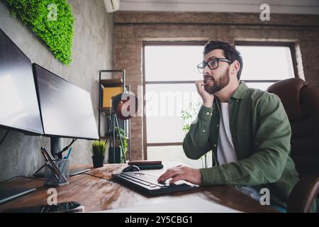 Foto eines professionellen IT-Spezialisten jungen Mannes beißen Fingernägel Computer Desktop Loft Innenraum Büro drinnen Stockfoto