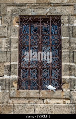 Dekorativer schmiedeeiserner Grill über Buntglasfenster an der historischen Kirche, Sicherheitsschmiedearbeiten an zerbrechlichen Fenstern auf dem denkmalgeschützten historischen bui Stockfoto