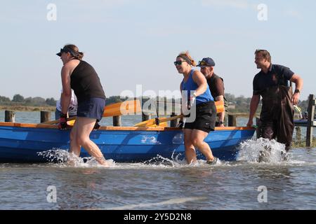 Mersea Island, Großbritannien. September 2024. Das jährliche Rennen um die Insel fand heute um Mersea Island in Essex statt. Segelschiffe aller Art nehmen an der Veranstaltung Teil. Die Besatzungen müssen ihre Boote über den Strood transportieren, der einzigen Straße auf und vor der Insel, die bei außergewöhnlich hohen Fluten überschwemmt wird. Credit:Eastern Views/Alamy Live News Stockfoto