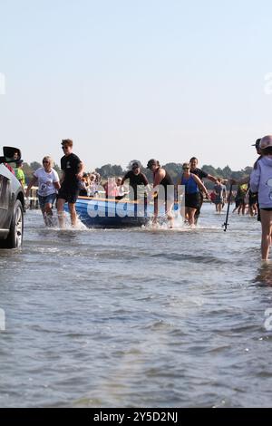 Mersea Island, Großbritannien. September 2024. Das jährliche Rennen um die Insel fand heute um Mersea Island in Essex statt. Segelschiffe aller Art nehmen an der Veranstaltung Teil. Die Besatzungen müssen ihre Boote über den Strood transportieren, der einzigen Straße auf und vor der Insel, die bei außergewöhnlich hohen Fluten überschwemmt wird. Credit:Eastern Views/Alamy Live News Stockfoto