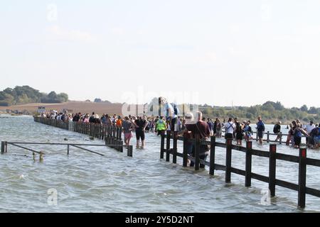 Mersea Island, Großbritannien. September 2024. Das jährliche Rennen um die Insel fand heute um Mersea Island in Essex statt. Segelschiffe aller Art nehmen an der Veranstaltung Teil. Die Besatzungen müssen ihre Boote über den Strood transportieren, der einzigen Straße auf und vor der Insel, die bei außergewöhnlich hohen Fluten überschwemmt wird. Credit:Eastern Views/Alamy Live News Stockfoto