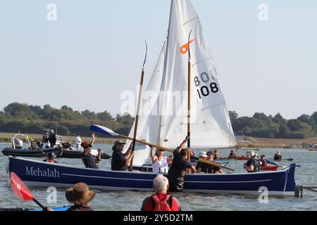 Mersea Island, Großbritannien. September 2024. Das jährliche Rennen um die Insel fand heute um Mersea Island in Essex statt. Segelschiffe aller Art nehmen an der Veranstaltung Teil. Die Besatzungen müssen ihre Boote über den Strood transportieren, der einzigen Straße auf und vor der Insel, die bei außergewöhnlich hohen Fluten überschwemmt wird. Credit:Eastern Views/Alamy Live News Stockfoto