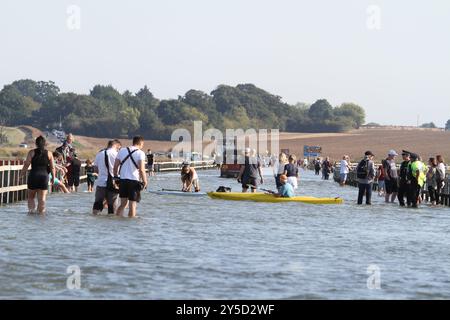 Mersea Island, Großbritannien. September 2024. Das jährliche Rennen um die Insel fand heute um Mersea Island in Essex statt. Segelschiffe aller Art nehmen an der Veranstaltung Teil. Die Besatzungen müssen ihre Boote über den Strood transportieren, der einzigen Straße auf und vor der Insel, die bei außergewöhnlich hohen Fluten überschwemmt wird. Credit:Eastern Views/Alamy Live News Stockfoto