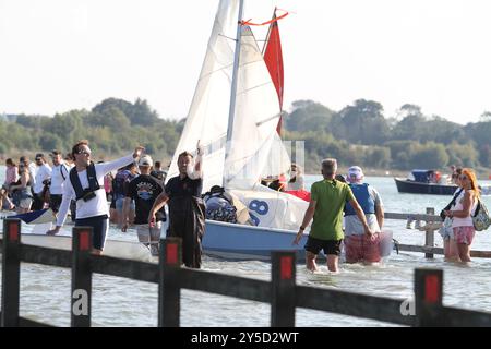 Mersea Island, Großbritannien. September 2024. Das jährliche Rennen um die Insel fand heute um Mersea Island in Essex statt. Segelschiffe aller Art nehmen an der Veranstaltung Teil. Die Besatzungen müssen ihre Boote über den Strood transportieren, der einzigen Straße auf und vor der Insel, die bei außergewöhnlich hohen Fluten überschwemmt wird. Credit:Eastern Views/Alamy Live News Stockfoto