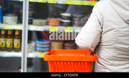 Frau, die im Supermarkt einen leeren Korb hält Stockfoto