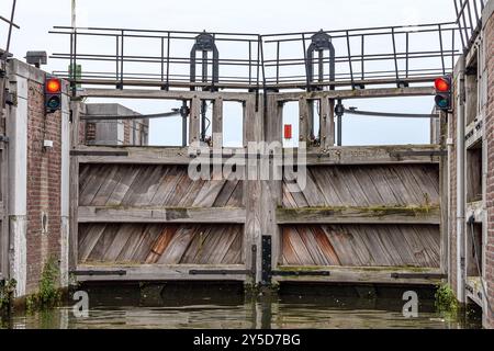 Altes hölzernes Tor am Eingang oder Ausgang der alten und historischen Schleuse Nr. 20, Schifffahrtskanal für Schiffe außerhalb der Stadt Maastricht, rote Ampel, Clou Stockfoto