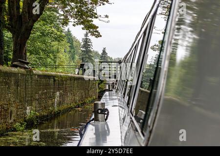 Seite eines Schiffes, das in manueller Schleuse Nr. 19 fährt, Navigationskanal für kleine Boote außerhalb der Stadt Maastricht, Laub von Bäumen im Hintergrund, bewölkt d Stockfoto