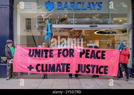 Bath, UK. September 2024. Die Demonstranten stehen vor der Barclays Bank, während sie an einem protestmarsch durch das Zentrum von Bath teilnehmen. Barclays wurde für seine Investitionen in Waffenlieferanten kritisiert. Der Protest "Kampf gegen den Klimawandel - Krieg nicht anheizen" wurde von der Extinction Rebellion Bath und der Bath-Gruppe "Stop war" organisiert und fand statt, um die Tatsache zu unterstreichen, dass Großbritannien sieben Mal so viel für Waffen ausgibt wie für den Klimawandel. Quelle: Lynchpics/Alamy Live News Stockfoto