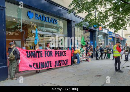 Bath, UK. September 2024. Die Demonstranten stehen vor der Barclays Bank, während sie an einem protestmarsch durch das Zentrum von Bath teilnehmen. Barclays wurde für seine Investitionen in Waffenlieferanten kritisiert. Der Protest "Kampf gegen den Klimawandel - Krieg nicht anheizen" wurde von der Extinction Rebellion Bath und der Bath-Gruppe "Stop war" organisiert und fand statt, um die Tatsache zu unterstreichen, dass Großbritannien sieben Mal so viel für Waffen ausgibt wie für den Klimawandel. Quelle: Lynchpics/Alamy Live News Stockfoto