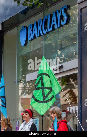 Bath, UK. September 2024. Die Demonstranten stehen vor der Barclays Bank, während sie an einem protestmarsch durch das Zentrum von Bath teilnehmen. Barclays wurde für seine Investitionen in Waffenlieferanten kritisiert. Der Protest "Kampf gegen den Klimawandel - Krieg nicht anheizen" wurde von der Extinction Rebellion Bath und der Bath-Gruppe "Stop war" organisiert und fand statt, um die Tatsache zu unterstreichen, dass Großbritannien sieben Mal so viel für Waffen ausgibt wie für den Klimawandel. Quelle: Lynchpics/Alamy Live News Stockfoto