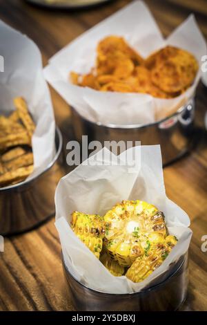 Rustikaler gegrillter Zuckermais und andere einfache Snacks auf dem Tisch Stockfoto