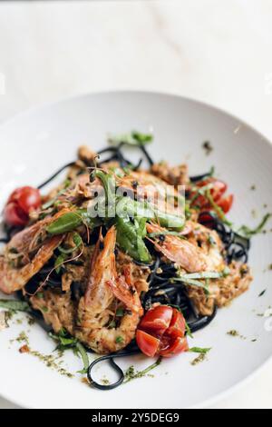 Gourmet-Essen gegrillte Garnelen und Gemüse auf Pasta-Mahlzeit mit schwarzer Tintenfisch-Tinte Stockfoto