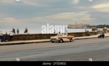 739 alter amerikanischer Oldtimer in weiß und Bronze - Buick von 1955 - fährt auf der Malecon Promenade, Einheimische auf der Uferbrüstung. Havanna-Kuba. Stockfoto