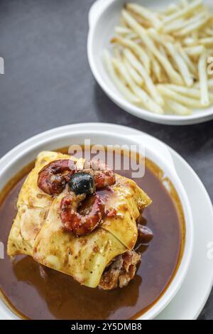 Berühmte Francesinha traditioneller Fleischkäse und gegrilltes Sandwich mit würziger Sauce aus porto portugal Stockfoto