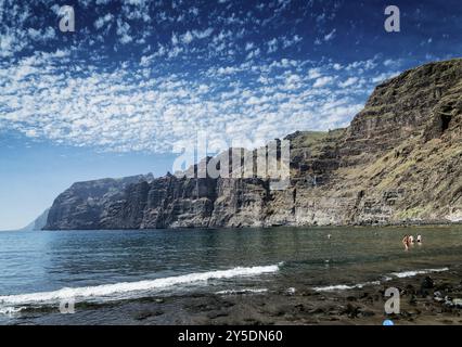 Touristen baden am schwarzen Sandstrand von los gigantes an den berühmten natürlichen Klippen im Süden der Insel teneriffa spanien Stockfoto