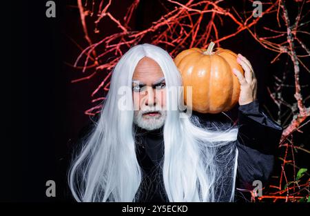 Teufelsvampirmann mit Halloween Kürbis. Zauberer hexer mit Kürbis am Halloween Abend. Zauberer mit Halloween Kürbis Jack-o-Laterne. Fantasie Stockfoto