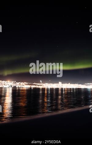 Nordlichter am Nachthimmel über dem Fjord neben Tromso City, Norwegen Stockfoto