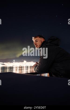 Mann auf Fjordkreuzfahrt unter aurora borealis in Tromso, Norwegen Stockfoto