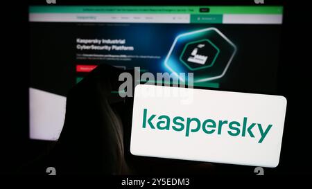 In dieser Abbildung hält eine Person ein Mobiltelefon mit dem Logo des russischen Cybersicherheitsunternehmens AO Kaspersky Lab vor der Unternehmenswebseite. Stockfoto