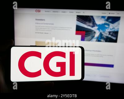 In dieser Abbildung hält eine Person ein Smartphone mit dem Logo des kanadischen IT-Unternehmens CGI Inc. Vor der Website. Stockfoto