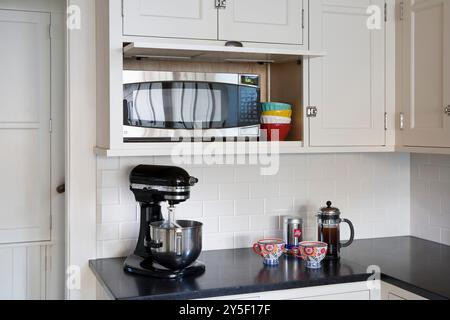 Ecke der weißen Küche mit eingebautem Mikrowellenschrank und offener Tür Stockfoto