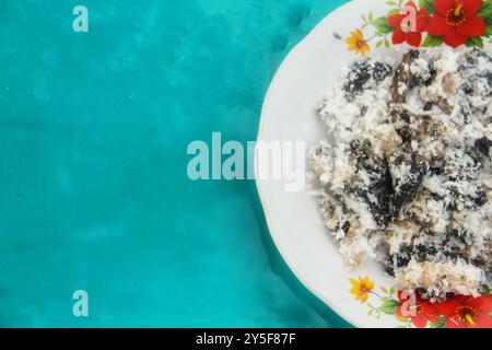 Gatot mit geriebenem Kokosnussbelag, Gatot ist ein typisches indonesisches Essen, das aus Maniok hergestellt wird, das einige Zeit getrocknet wird, um einen unverwechselbaren Bla zu produzieren Stockfoto