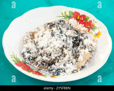 Gatot mit geriebenem Kokosnussbelag, Gatot ist ein typisches indonesisches Essen, das aus Maniok hergestellt wird, das einige Zeit getrocknet wird, um einen unverwechselbaren Bla zu produzieren Stockfoto