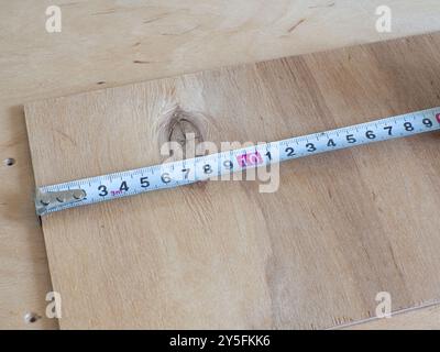 Nahaufnahme eines Maßbandes auf einer beigefarbenen hölzernen Hintergrundoberfläche Stockfoto