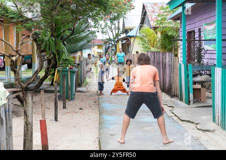 Teenager-Touristen spielen, interagieren mit lokalen Kindern in der Straße des Bajau People Village auf Labengki Insel, Sulawesi, Indonesien Stockfoto