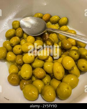 Grüne Oliven in weißer Schüssel mit Löffel. Hochwertige Fotos Stockfoto