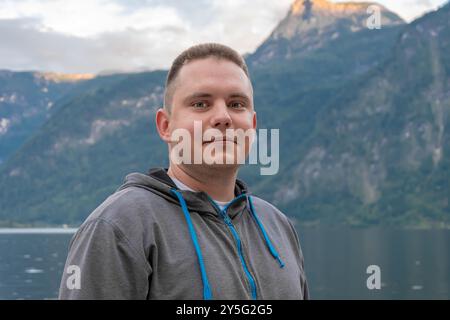 Ein 25-30-jähriger Mann steht an einem hölzernen Pier in der Nähe eines ruhigen Bergsees. Stockfoto