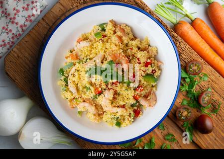 Couscous-Salat mit Gemüse und Garnelen. Tisch mit Draufsicht und Dekoration. Stockfoto