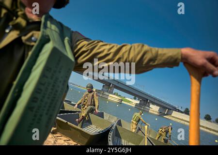 Die Reenactoren warteten darauf, in originalen Uniformen und mit originalen Waffen in die Ruderboote zu steigen. Diese Reenactors üben die Nachstellung der „Kreuzung der Waal“. Die Praxis fand am Fluss Waal in einem Überlaufgebiet namens Nevengeul statt. Hier befindet sich auch das Denkmal auf dem Deich. Vor 80 Jahren überquerten 260 Soldaten der 82. Luftlandedivision die Waal in 26 Segelbooten, um die Waal-Brücke gleichzeitig von Süden und Osten anzugreifen. Die Hälfte der 260 Soldaten wurde verletzt und 48 wurden bei dieser Aktion getötet. Es ist nicht bekannt, wie viele deutsche Soldaten darin starben Stockfoto