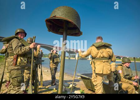 Nijmegen, Gelderland, Niederlande. September 2024. Reenactoren, die vom Rudern ausgeruht wurden. Diese Reenactors üben die Nachstellung der „Kreuzung der Waal“. Die Praxis fand am Fluss Waal in einem Überlaufgebiet namens Nevengeul statt. Hier befindet sich auch das Denkmal auf dem Deich. Vor 80 Jahren überquerten 260 Soldaten der 82. Luftlandedivision die Waal in 26 Segelbooten, um die Waal-Brücke gleichzeitig von Süden und Osten anzugreifen. Die Hälfte der 260 Soldaten wurde verletzt und 48 wurden bei dieser Aktion getötet. Es ist nicht bekannt, wie viele deutsche Soldaten bei dieser Aktion starben. Stockfoto