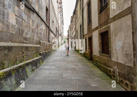 Touristenfrau, die durch die engen Gassen des historischen Zentrums von Santiago de Compestela, Galicien, spaziert. Stockfoto