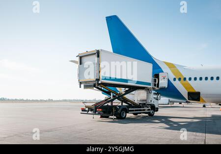 Catering Truck in der Nähe des Passagierflugzeugs. Das Flugzeug wird für einen Flug vorbereitet. Rollweg und Start- und Landebahn im Hintergrund leeren. Stockfoto