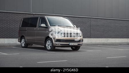 Brauner VW Transporter vor grauer Wand. Vorderansicht des Volkswagen T6-Lieferwagens in urbaner Umgebung - geparkt in der Nähe einer anthrazitfarbenen Wand. Stockfoto