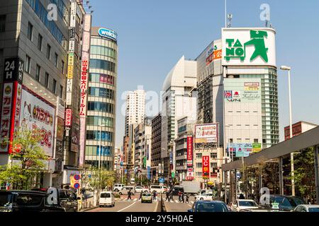 Blick entlang von der mittleren Otakibashi-dori Straße in Shinjuku West. Hochhäuser auf beiden Seiten der zweispurigen Straße. Blauer Himmel und heller Sonnenschein. Stockfoto