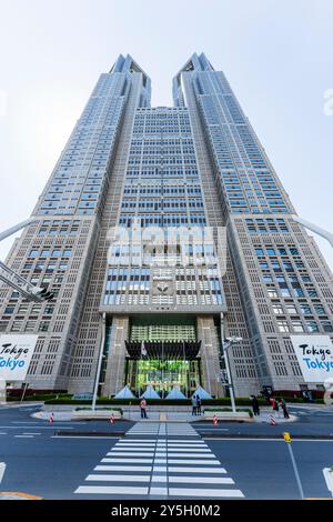 Blick vom Boden aus auf der anderen Straßenseite direkt vor dem riesigen Tokyo Metropolitan Government Building vor einem blassblauen Himmel. Stockfoto