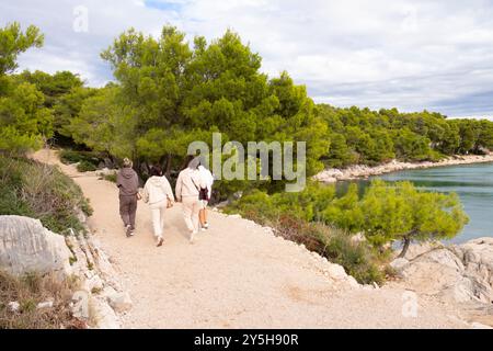 Tribunj, Kroatien - 13. September 2024: Menschen wandern auf einem Küstenwanderweg in Kiefernwäldern am felsigen Meer Stockfoto