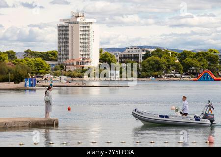 Vodice, Kroatien - 14. September 2024: Junge Frau wartet auf der Strandpier, um an Bord zu gehen, wenn das Boot anlegt Stockfoto