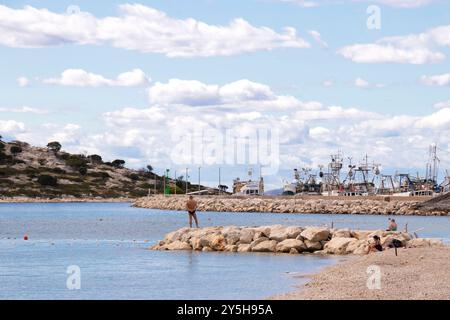 Tribunj, Kroatien - 14. September 2024: Strand in der Nebensaison mit wenigen Menschen und Fischerbooten im Hintergrund Stockfoto