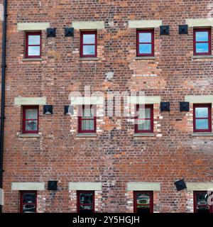 Muster aus Ziegelwerk, Wohnungsfenstern und strukturellen Stützen in einem viktorianischen Lagerhaus am Hafen, das für das städtische Leben restauriert wurde Stockfoto