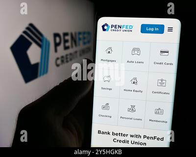 In dieser Abbildung hält eine Person ein Smartphone mit der Webseite des US-amerikanischen Unternehmens Pentagon Federal Credit Union (PenFed) vor dem Logo. Stockfoto