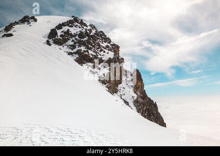 Gruppe von Kletterern erreicht den Gipfel Kasbeks in Georgien. Geben Sie niemals auf und durchdrängen Sie das Konzept der Lebensschwierigkeiten. Mann, der hart arbeitet, um einen Mo hinaufzuklettern Stockfoto