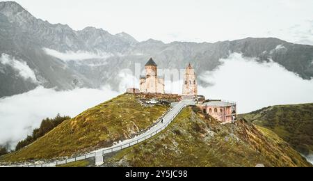 Gergeti trinity Kirche nach Sonnenuntergang aus der Vogelperspektive, Georgia. Stepanstminda berühmtes Wahrzeichen auf einem Hügel mit nebeligen kaukasus-Bergen im Hintergrund Stockfoto