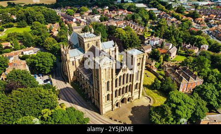 Blick aus der Vogelperspektive auf eine große, historische Kathedrale, umgeben von üppigem Grün und Wohngebäuden. Die Kathedrale verfügt über hohe Türme und einen komplizierten Bogen Stockfoto