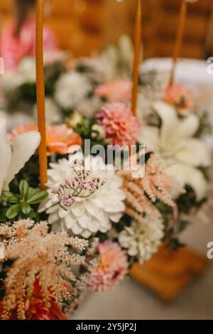 Eine Nahaufnahme eines wunderschönen Blumenarrangements mit weichen Pastellfarben und zarten Texturen, die einen Tisch in einer rustikalen Umgebung schmücken. Stockfoto