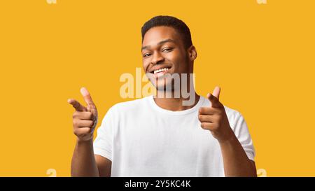 Aufgeregter schwarzer Kerl, der Sie über orangefarbenem Hintergrund wählt Stockfoto