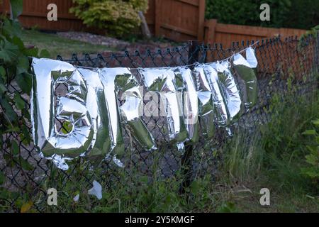 Silberne Happy Birthday-Worte aus aufblasbaren Ballons am Gartenzaun in england großbritannien. Stockfoto